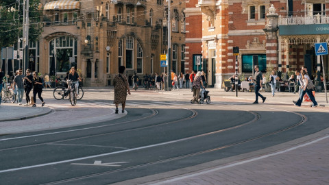 kruispunt in Amsterdam waarop je een tramlijn, fietspad, weg en weggebruikers afbeeld ziet