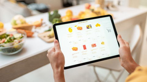 een vrouw houdt een tablet vast waarop de website van een webwinkel openstaat bij de pagina met fruit