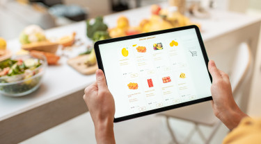 een vrouw houdt een tablet vast waarop de website van een webwinkel openstaat bij de pagina met fruit