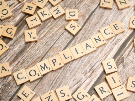 letters liggen rommelig op tafel, een aantal letters vormen het woord compliance 